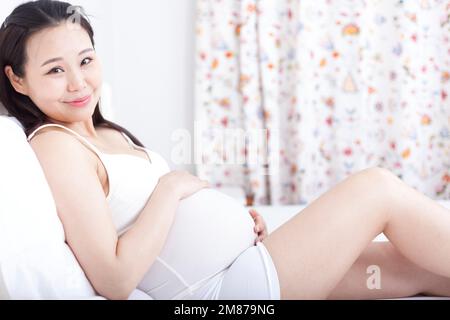 Schwangere Frauen saßen auf dem Bett, um sich auszuruhen Stockfoto