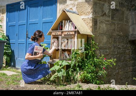 Frau nimmt die kostenlosen Bücher über die Straßenbibliothek Stockfoto