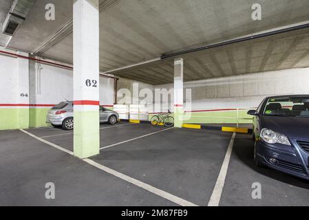 Neu erbaute Garage mit breiten Parkplätzen und Gassen mit Betonböden, weißen Linien auf dem Boden und geparkten Fahrzeugen Stockfoto