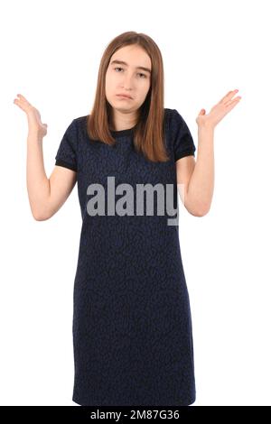 Ein junges, hübsches Mädchen in einem dunkelblauen Kleid auf weißem Hintergrund, ahnungslos und verwirrter Ausdruck mit erhobenen Armen und Händen. Zweifelhaftes Konzept. Stockfoto