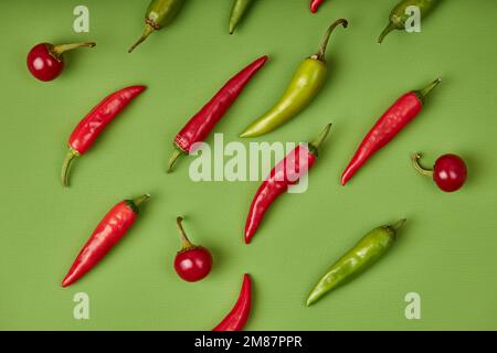 Flach Lay Zusammensetzung mit vielen heißen Chilischoten auf grünem Hintergrund. Frisches Obst Gemüse Konzept. Draufsicht Stockfoto