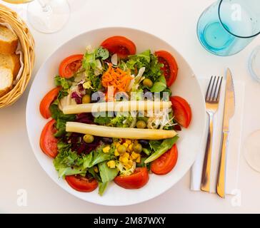 Traditioneller spanischer gemischter Salat aus Erbsen, Mais, Tomaten, Salat, Oliven, Karotten, Spargel, Zwiebeln Stockfoto