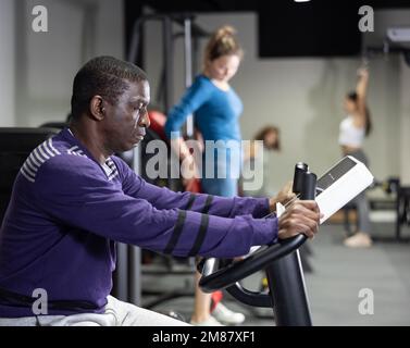 Afrikanischer Mann mit Fahrrad im Fitnessstudio Stockfoto