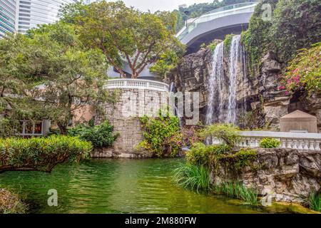 Künstlicher Wasserfall im Park „Hong-Kong“ und Teich und Natur und Berg und Wolkenkratzer Og Central Island (und District) Stockfoto