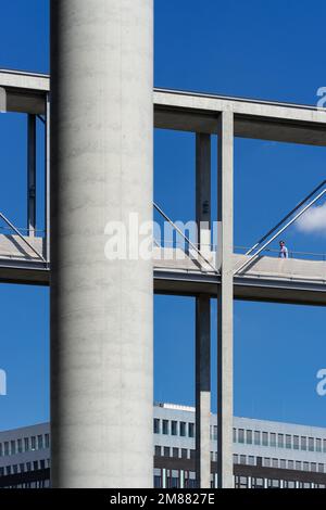 Mann, der tagsüber über über die Marie-Elisabeth Lüders-Fußgängerbrücke in Berlin geht; abstrakte Geometrie-Architektur isoliert Stockfoto