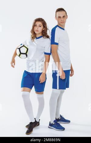 Fußballspielerin und Fußballerin in weißer Uniform mit isoliertem Ball Stockfoto