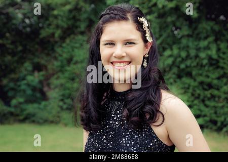 Nahaufnahme eines lächelnden Teenagers in schwarzem Racerback-Ballkleid mit Pailletten Stockfoto