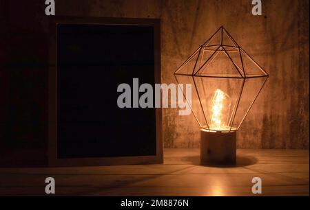 Eine einzelne Glühbirne, die im Dunkeln hell leuchtet. Stockfoto