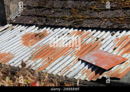 Ein altes Haus, das sich in einer Renovierung befand, mit rostigem Metall und moosbedeckten Fliesen auf dem Dach Stockfoto