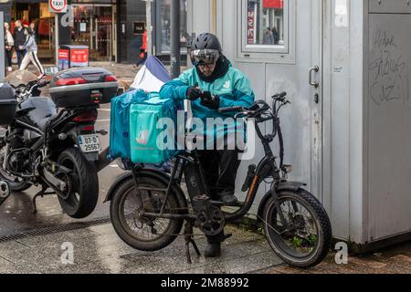 Deliveroo-Fahrer macht eine Pause in Cork, Irland. Stockfoto