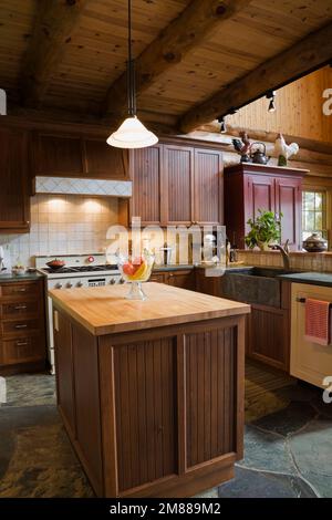 Küche im Landhausstil mit Insel- und Schieferfliesenboden in handgefertigtem skandinavischem Fichtenholz. Stockfoto