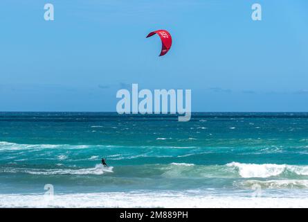 GOLD COAST, QUEENSLAND, AUSTRALIEN. 7. Januar 2023. Drachenboarder surfen auf den Wellen im Surferparadies mit einem roten Drachen und blauem Himmel. Stockfoto