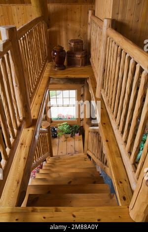 Zwischengeschoss mit rustikalem Geländer und Holztreppe, die zum unteren Stockwerk im handgefertigten skandinavischen Fichtenholz führt. Stockfoto