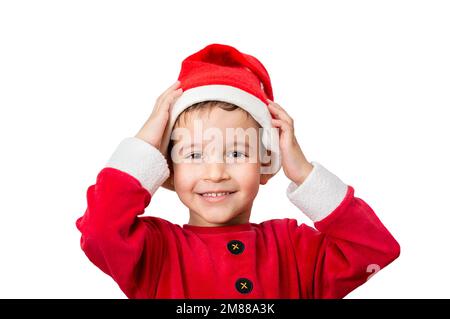 Studioaufnahme eines fröhlichen Jungen, der posiert und seinen Weihnachtsmann-Hut aufsetzt, während er auf weißem Hintergrund steht. Stockfoto