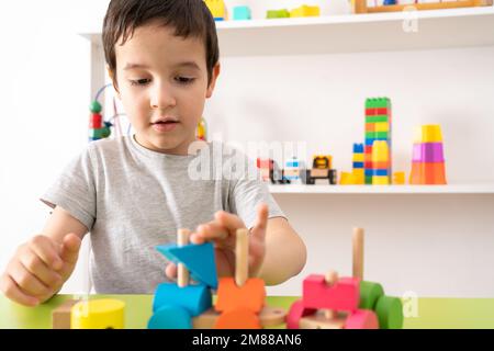 Aufnahme eines Kindes mit Holzspielzeug. Das Kind sammelt einen Sortierer. Pädagogische Logik-Spielzeug für Kinder.Spiele für Kind Stockfoto