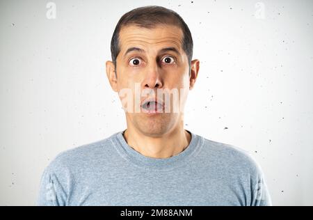 Porträt eines schockierten jungen Mannes vor grauem Hintergrund Stockfoto