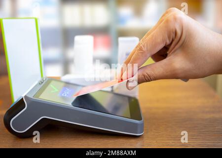 Mobile Payment-Konzept. Der Kunde zahlt mit einer drahtlosen oder kontaktlosen Kreditkarte und einem Zahlungsterminal mit NFC-Technologie in der Apotheke Stockfoto