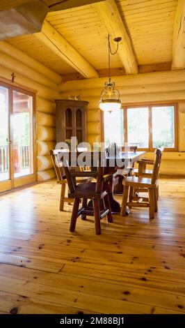 Esstisch aus Zedernholz und Stühle mit hoher Rückenlehne im Speisesaal im Blockhaus im skandinavischen Stil, Stockfoto
