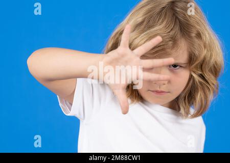 Nahaufnahme eines Kindes mit Stoppgesten auf isoliertem blauem Hintergrund. Kind mit Warnsymbol, Handzeichen Nr. Kinderschutz, Mobbing, Missbrauch Stockfoto