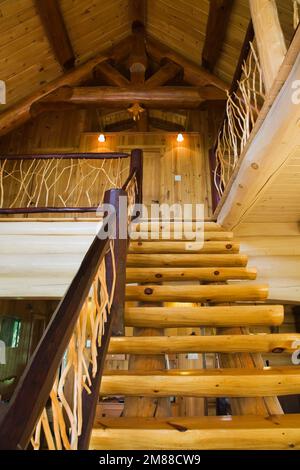 Treppen aus weißem Kiefernholz mit Zedernholzgeländern, die zum oberen Stockwerk in einem Blockhaus im skandinavischen Stil führen. Stockfoto