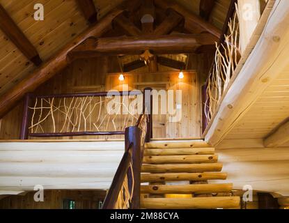 Treppen aus weißem Kiefernholz mit Zedernholzgeländern, die zum oberen Stockwerk in einem Blockhaus im skandinavischen Stil führen. Stockfoto