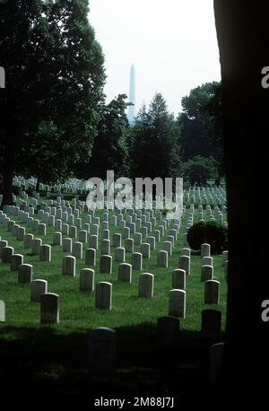 Auf dem Arlington National Cemetery befinden sich weiße Grabsteine an einem Hügel. Das Washington Monument ist in der Ferne zu sehen. Basis: Arlington Bundesstaat: Virginia (VA) Land: Vereinigte Staaten von Amerika (USA) Stockfoto