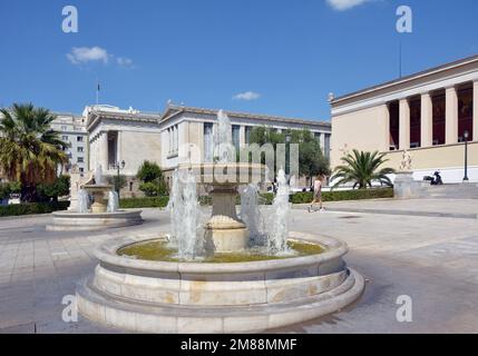 Brunnen vor dem zentralen Gebäude der Nationalen und Kapodistrianischen Universität von Athen, mit der Nationalbibliothek im Hintergrund Stockfoto