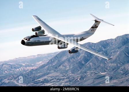 Luft-Luft, Seitenansicht des C-141B Starlifters eines 63. Airlift Wings, „Spirit of the Inland Empire“, wenn es sich nach links bewegt, mit den San Bernardino Bergen im Hintergrund, für die Landung in Norton. Exaktes Datum Aufnahme Unbekannt. Basis: Luftwaffenstützpunkt Norton Bundesstaat: Kalifornien (CA) Land: Vereinigte Staaten von Amerika (USA) Stockfoto