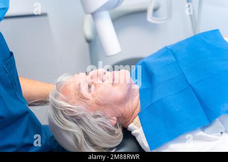 Zahnklinik, ältere Frau, die beim Zahnarzt liegt, bei der Prothesenuntersuchung Stockfoto