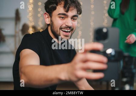 Mann, der seine Frau in einem neuen Zuhause filmt, mit dem Handy auf dem Smartphone. Aufnahme lustiger viraler und aktiver Videos für soziale Medien. Stockfoto