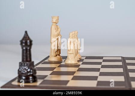 Schachmatt! Der helle König ist bei B1, die hellen Bauern bei A2, B2 und C2, der dunkle Turm bei H1. Nahaufnahme mit den einzigen Lichtelementen im Fokus. Stockfoto