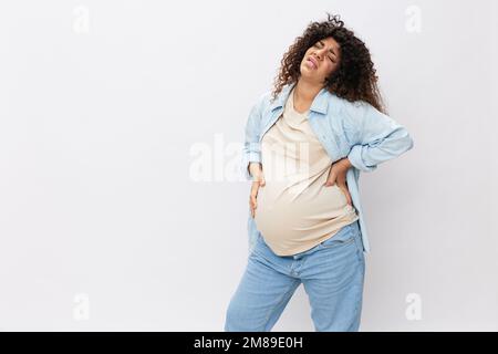 Schwangere Frau müde, Kopfschmerzen und Bauchschmerzen, schwere Schwangerschaft, letzten Monat vor der Geburt auf weißem isoliertem Hintergrund in T-Shirt mit blauem Stockfoto