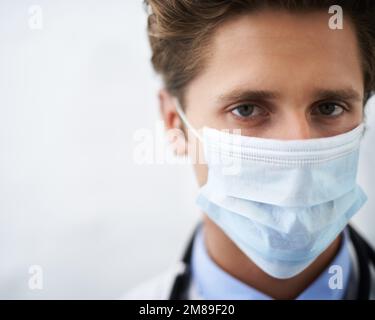 Ich nehme Ihre Gesundheit ernst. Nahaufnahme eines ernstaussehenden jungen Arztes mit Operationsmaske. Stockfoto