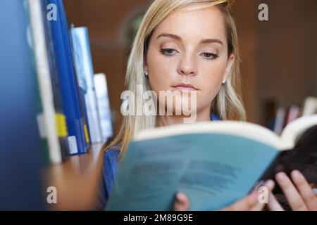 Unsere Universität hat die beste Bibliothek. Ein attraktiver junger Student, der ein Buch lese. Stockfoto