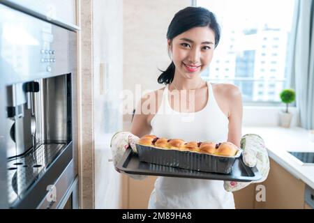 Die junge Frau, die in der Küche Brot backt Stockfoto