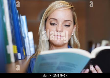 Unsere Universität hat die beste Bibliothek. Ein attraktiver junger Student, der ein Buch lese. Stockfoto