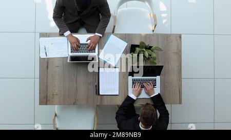 Zwei erfolgreiche lächelnde Geschäftsleute arbeiten an einem Notebook. Blick von oben Stockfoto