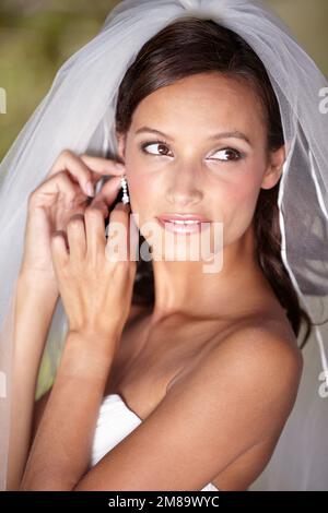 Das letzte Detail. Wunderschöne Braut, die ihre Ohrringe an ihrem Hochzeitstag angepasst hat. Stockfoto