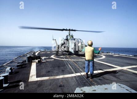 Ein Flugzeugführer signalisiert dem Piloten eines Marine Utility/Attack Helicopter Squadron 257 (HMLA-257) AH-1 Sea Cobra-Kanonenschiffs auf dem Hubschrauberdeck der geführten Raketenfregatte USS NICHOLAS (FFG-47) während des ernsthaften Willens, Eine Konvoi-Mission, bei der zurückgewiesene Kuwait-Tanker von US-Marineschiffen durch die Gewässer des Golfs begleitet werden. Betreff Betrieb/Serie: ERNSTWILLE Land: Unbekannt Stockfoto