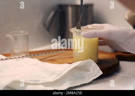 Jojobaöl und Wasser mit Löffel vermischen, die Becher im Labor Stockfoto