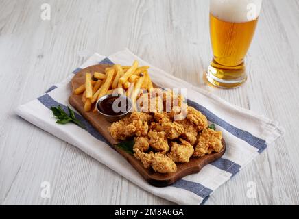 Hausgemachtes Popcorn Chicken mit BBQ-Sauce auf einem rustikalen Holzbrett, Seitenansicht. Stockfoto