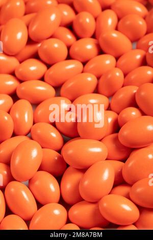 Schokoladendragee in Form eines Haufens. Orangefarbene Dragee-Schokolade mit Schokoladenfüllung. Schließen Stockfoto