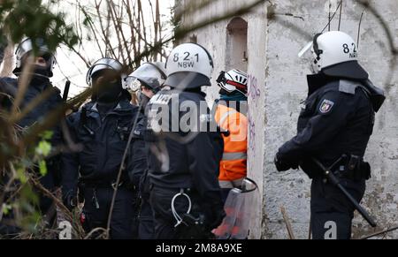 Erkelenz, Deutschland. 13. Januar 2023. Polizeibeamte stehen am dritten Tag der Räumung des Braunkohlendorfes Lützerath, das von Klimaschutzaktivisten besetzt war, vor dem Eingang zu einem Gebäude. Hier sollen sich Aktivisten in einem Tunnel verbarrikadiert haben. Das Energieunternehmen RWE will die unter Lützerath liegende Kohle ausheben - zu diesem Zweck soll das Weiler auf dem Gebiet der Stadt Erkelenz am Braunkohlebergwerk Garzweiler II abgerissen werden. Kredit: Rolf Vennenbernd/dpa/Alamy Live News Stockfoto