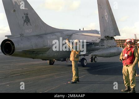 Ein Flugzeugdirektor steht hinter einem Angriffsgeschwader 37 (VA-37) A-7E Corsair II, als er einem anderen Flugzeug auf dem Cockpit des Flugzeugträgers USS FORRESTAL (CV-59) während der Allied Forces Exercise Team Work '88 signalisiert. Betreff Operation/Serie: TEAMARBEIT '88 Land: Nordatlantik Stockfoto