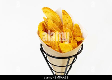 Im Ofen gebackene Kartoffelsplitter mit Meersalz und Kräutern. Pommes Frites in einer recycelbaren Papiertüte, beliebtes Fast Street Food Stockfoto