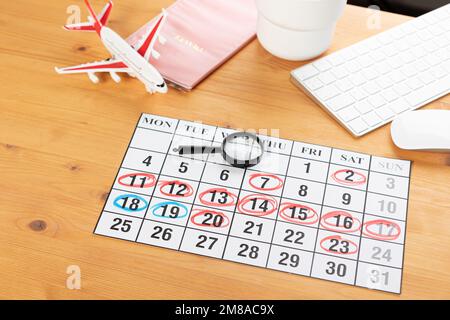 Kalender und Erinnerungen für Geschäftsreisen, Reisen und Urlaub. Gleiter auf dem Schreibtisch mit Flugzeug und Lupe, Stift und Tastatur. Markierung wichtig Stockfoto