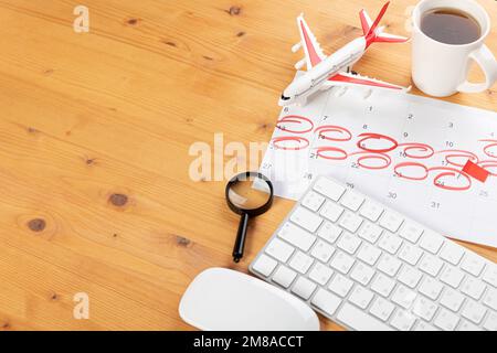 Kalender und Erinnerungen für Geschäftsreisen, Reisen und Urlaub. Gleiter auf dem Schreibtisch mit Flugzeug und Lupe, Stift und Tastatur. Markierung wichtig Stockfoto