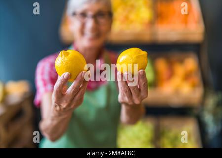 Ein Arbeiter im Obst- und Gemüseladen hält Zitronen. Nahaufnahme von Zitrone. Stockfoto