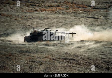 Ein M-1A1 Abrams Hauptwaffenpanzer der 24. Infanteriedivision (mechanisiert) wirbelt während einer Feuerübung im National Training Center eine Staubwolke auf. Basis: Fort Irwin Bundesstaat: Kalifornien (CA) Land: Vereinigte Staaten von Amerika (USA) Stockfoto