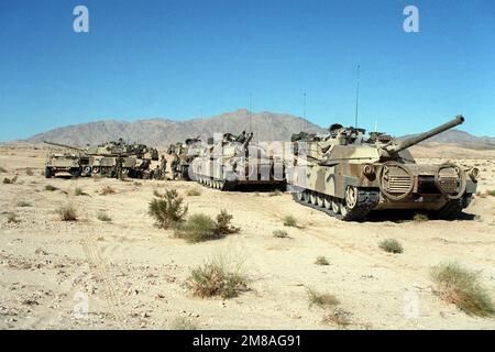 Mitglieder der 24. Infanterie-Division (mechanisiert) versammeln sich bei einer Übung im National Training Center in der Nähe eines ihrer geparkten M-1A1 Abrams Hauptpanzer. Basis: Fort Irwin Bundesstaat: Kalifornien (CA) Land: Vereinigte Staaten von Amerika (USA) Stockfoto